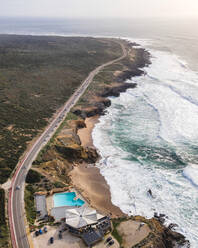 Luftaufnahme einer schönen einsamen Straße mit Fahrzeugen entlang der südportugiesischen Küste mit Blick auf den Atlantik raues Meer, Cascais, Portugal. - AAEF16590