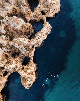 Luftaufnahme von Menschen beim Kajakfahren entlang der Küste in der Nähe der Höhlen in Ponta da Piedade mit malerischen Klippen im Sommer, Lagos, Algarve-Region, Portugal. - AAEF16609