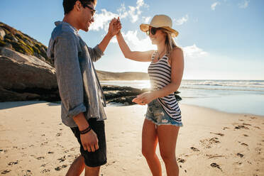 Shot of young man and woman dancing on the beach on a summer day. Romantic young couple dancing on the beach. - JLPSF27073