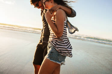 Außenaufnahme eines jungen Paares, das am Meer spazieren geht. Junger Mann und Frau, die an einem Sommertag gemeinsam am Strand spazieren gehen. - JLPSF27086