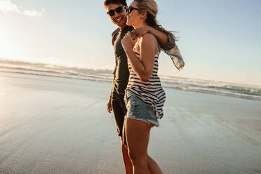 Aufnahme eines jungen Mannes und einer Frau, die an einem Sommertag am Strand spazieren gehen. Romantisches junges Paar, das am Strand spazieren geht. - JLPSF27087