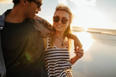 Porträt einer Frau mit ihrem Freund am Strand. Junges Paar am Meeresufer bei Sonnenuntergang. - JLPSF27089