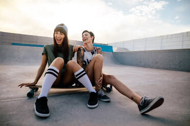 Zwei weibliche Skateboarderinnen lachen und haben Spaß, zwei Freundinnen hängen im Skatepark ab. - JLPSF27125