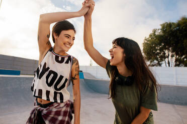 Zwei aufgeregte Freundinnen geben sich im Skatepark die Klinke in die Hand. Schöne Frauen haben eine tolle Zeit im Skatepark. - JLPSF27131