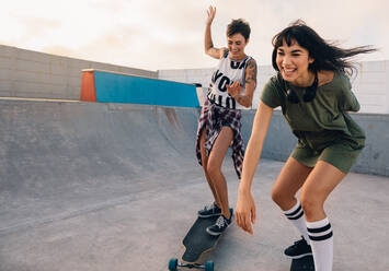 Junge Hipster-Mädchen fahren auf Skateboards und haben Spaß. Weibliche Freunde zusammen Skateboarding im Skatepark. - JLPSF27132