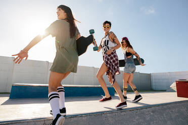 Drei Freundinnen laufen und springen über die Rampe des Skateparks. Frauen skaten im Skatepark. - JLPSF27151