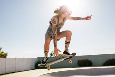 Weibliche Skaterin übt Skateboarding im Skatepark. Frauen machen Ollie auf Skateboard. - JLPSF27160