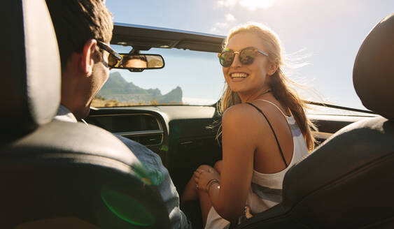 Rückansicht eines Paares, das in einem Auto unterwegs ist: Mann und Frau machen einen Ausflug in einem Cabrio. - JLPSF27192