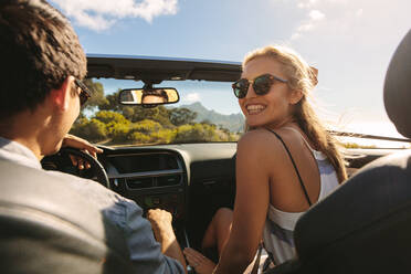 Schöne Frau, die mit ihrem Freund einen Roadtrip macht. Ein Paar, das in einem Cabrio auf eine lange Fahrt geht. - JLPSF27194