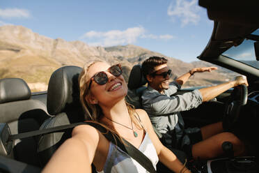 Beautiful woman going on road trip with her boyfriend. Young couple enjoying on road trip in a convertible car. - JLPSF27202