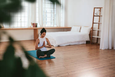 Schöne junge Frau macht Yoga-Übung auf Matte zu Hause. Fitness-Frau meditiert in Lotus-Pose. - JLPSF27222