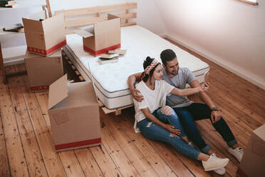 Young couple moving in new house and taking self portrait with smart phone. Young man and woman sitting on floor making selfie with mobile phone. - JLPSF27239