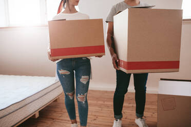 Junges Paar mit großen Kartons beim Umzug in ein neues Haus. Ausschnitt von Mann und Frau, die große Kartons tragen und in ein neues Haus umziehen. - JLPSF27240