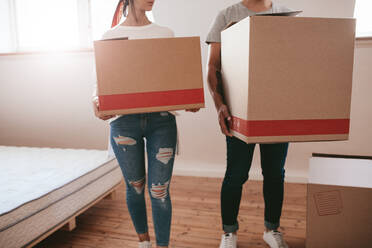 Young couple with big cardboard boxes moving to new place. Cropped shot of man and woman carrying big boxes and moving into new house. - JLPSF27240