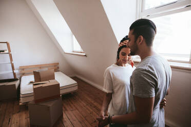 Young couple in love moving in a new home. Man and woman standing together in their new house. - JLPSF27244