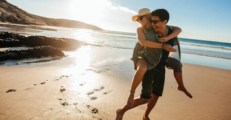 Young man giving his girlfriend a piggyback ride on the beach - a Royalty  Free Stock Photo from Photocase