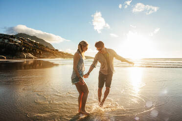 Schönes junges Paar hält sich an den Händen und genießt zusammen am Ufer. Glückliches junges romantisches Paar in der Liebe, das Spaß am schönen Strand hat. - JLPSF27271