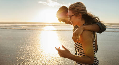 Side view shot of loving young couple enjoying a day on beach. Beautiful woman with her boyfriend walking on the seashore on a summer day. - JLPSF27284