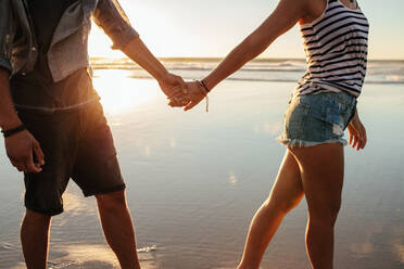 Cropped shot of young man and woman holding hands and walking on the shore. - JLPSF27291