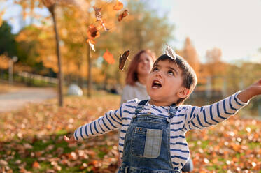 Adorable kleiner Junge wirft Blätter im Herbst Park und Spaß haben am sonnigen Tag - ADSF40059
