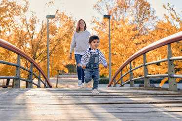 Sorgloser kleiner Junge und lächelnde Mutter verbringen Zeit zusammen im Herbst Park am sonnigen Tag - ADSF40060