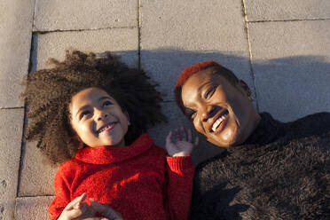 Smiling cute black and woman lying on floor - ADSF40112