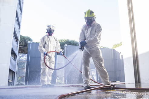 Zwei Feuerwehrleute desinfizieren das Innere eines Gebäudes - ADSF40158