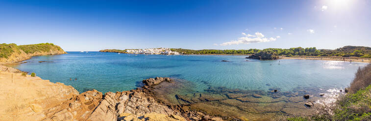 Spanien, Balearen, Menorca, Panoramablick auf eine Bucht im Sommer mit einem Dorf in der Ferne - SMAF02338