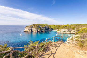 Spanien, Balearische Inseln, Menorca, Klippen von Cala Macarelleta im Sommer mit Holzzaun im Vordergrund - SMAF02362