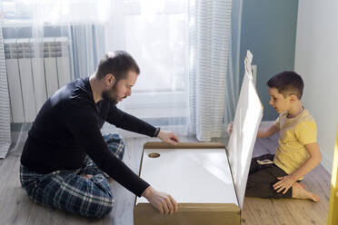 Vater und Sohn bauen den Tisch zu Hause zusammen - ONAF00229