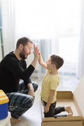 Vater gibt seinem Sohn in der Kiste zu Hause ein High-Five - ONAF00232