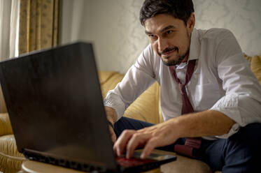 Entschlossener Geschäftsmann arbeitet zu Hause am Laptop - ANAF00416