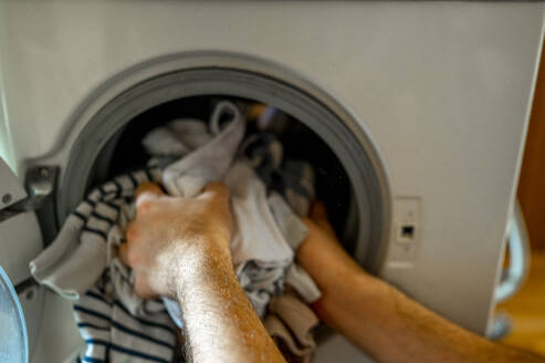Hände eines Mannes, der Kleidung aus der Waschmaschine nimmt - ANAF00422