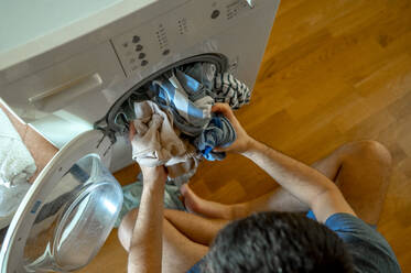 Mann lädt Wäsche in die Waschmaschine - ANAF00425