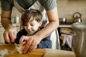 Vater bringt seinem Sohn in der Küche bei, Zwiebeln zu schneiden - ANAF00433