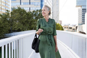 Ältere Frau in grünem Kleid geht auf einem Steg - OIPF02657