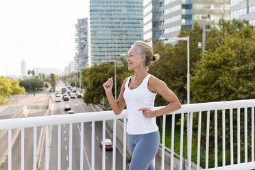 Woman jogging near railing in city - OIPF02671