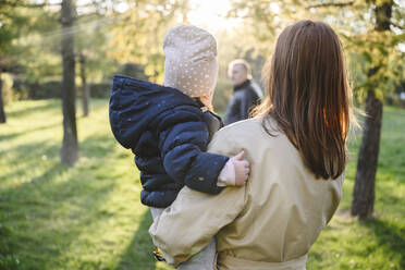 Mother carrying daughter in autumn park - EYAF02309