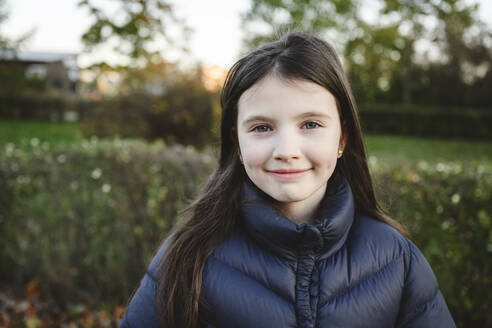 Smiling girl with long hair wearing padded jacket - EYAF02312