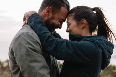 Seitenansicht eines romantischen jungen Paares, das im Freien zusammensteht. Junger Mann und Frau in Liebe. - JLPSF27343