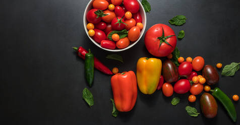 Tomaten, Chilis, Paprika und Dillblätter auf dem Tisch. Rote und gelbe Paprika neben Tomaten, Minze, Chilis und Dillblättern. - JLPSF27356
