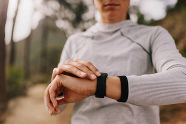 Close up of female athlete checking fitness progress on her smart watch. Woman runner using fitness app to monitor workout performance. - JLPSF27421