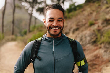 Portrait of healthy young caucasian man standing outdoors and smiling. Confident young male runner on country road. - JLPSF27422