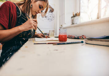 Image of beautiful woman drawing pictures in her workshop. Female artist painting in her studio. - JLPSF27427