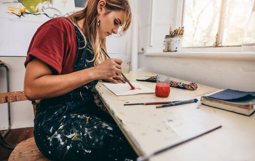 Seitenansicht einer schönen Künstlerin, die in ihrem Atelier Bilder malt. Junge Frau malt in ihrem Atelier. - JLPSF27428