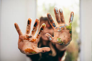 Nahaufnahme einer Künstlerin, die ihre unordentlichen Hände zeigt. Fokus auf die Hände der Malerin mit Farbe. - JLPSF27438