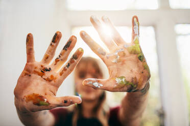 Close up of woman showing her messy hands. Focus on hands of female painter with color. - JLPSF27439