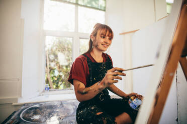 Indoor shot of female artist painting in studio. Woman painter painting in her workshop. - JLPSF27469