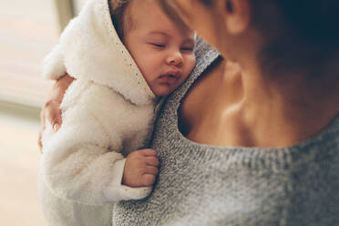 Nahaufnahme einer Frau, die ihren neugeborenen Jungen trägt. Ein süßer kleiner Junge schläft in den Armen seiner Mutter. - JLPSF27472