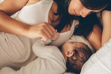 Mutter und Sohn auf dem Bett. Junge Frau mit einem schlafenden Jungen im Bett zu Hause. - JLPSF27496